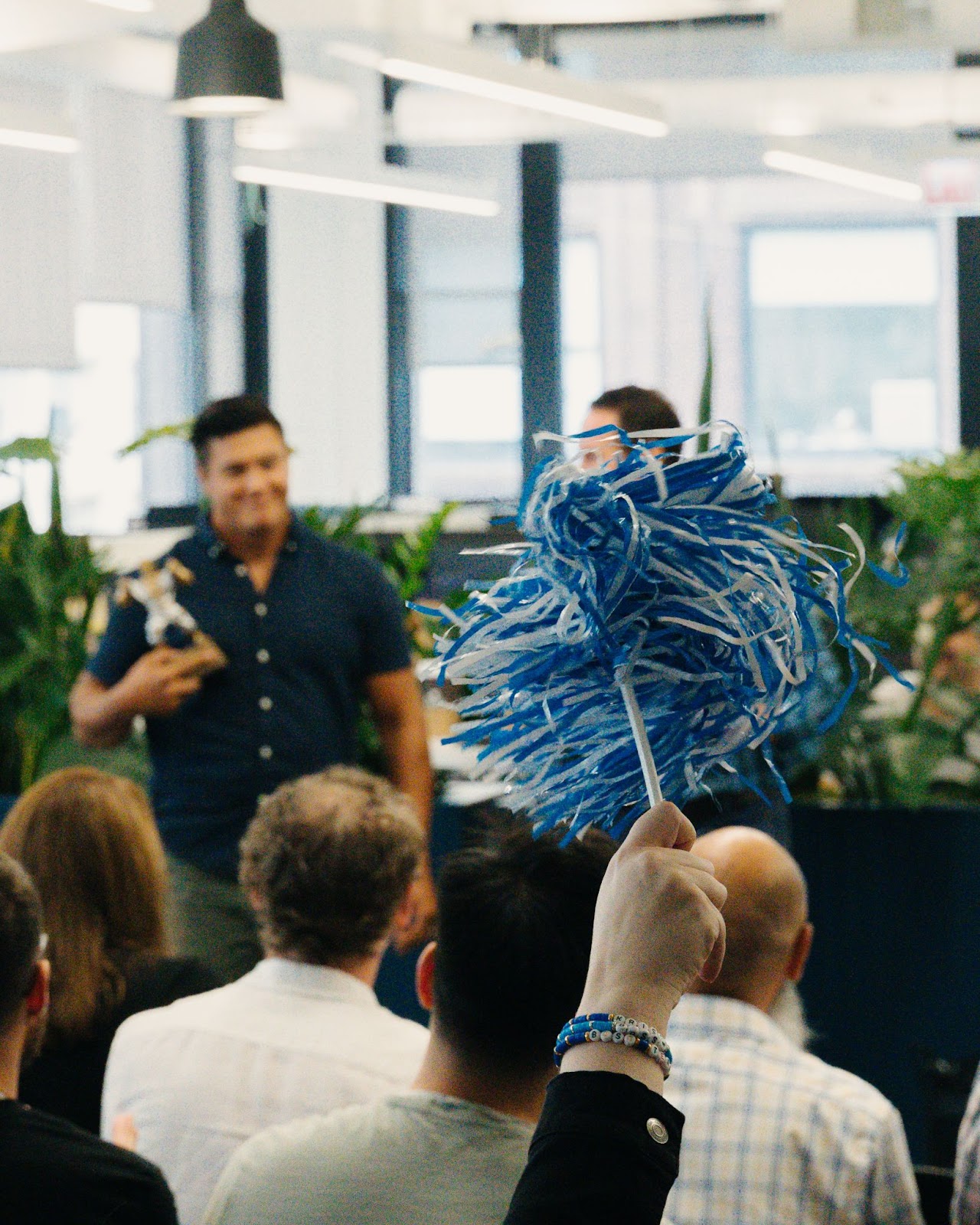 Snapsheet employeed waving blue and white pom pom in air to celebrate summer summit